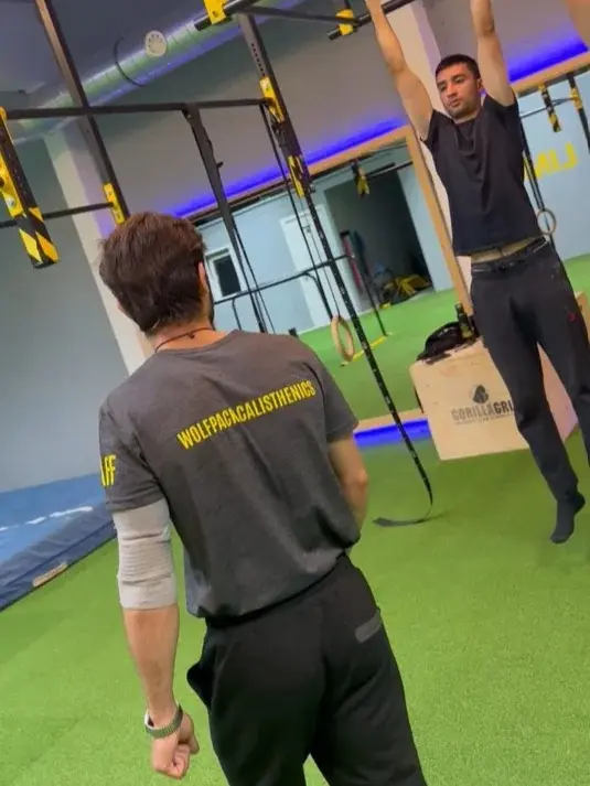 Een coach observeert een sporter aan de pull-upstang